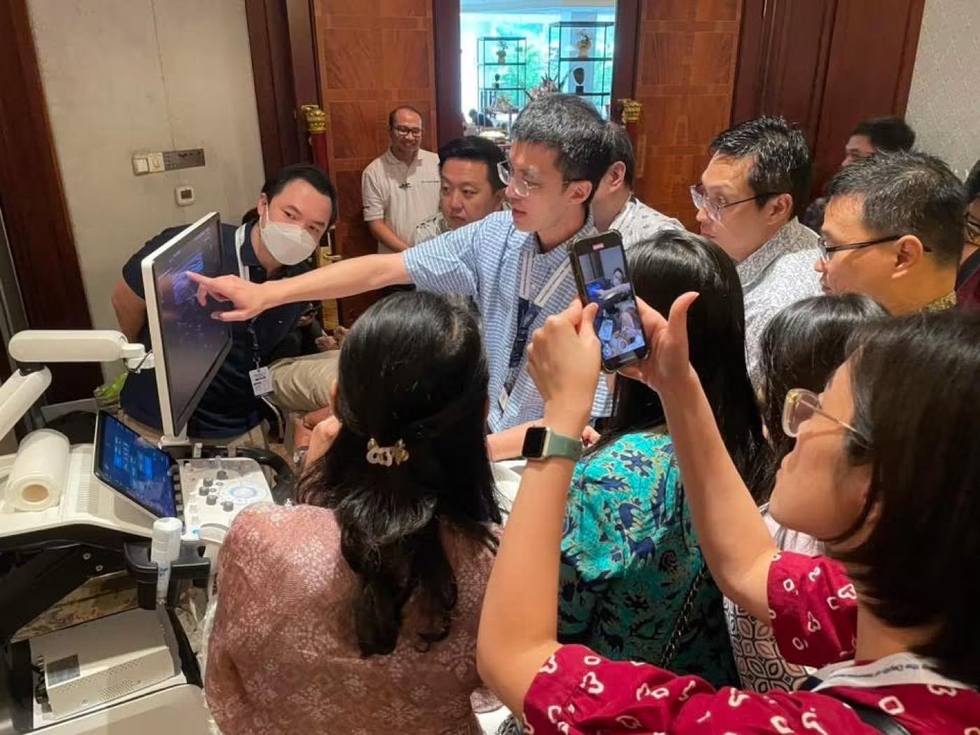 蘇炯睿醫師於國際工作坊進行超音波實作教學，多位醫師圍在超音波儀器前